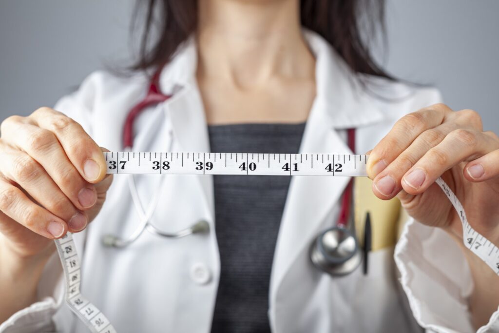 doctor with tape measure highlighting abdominal circumference